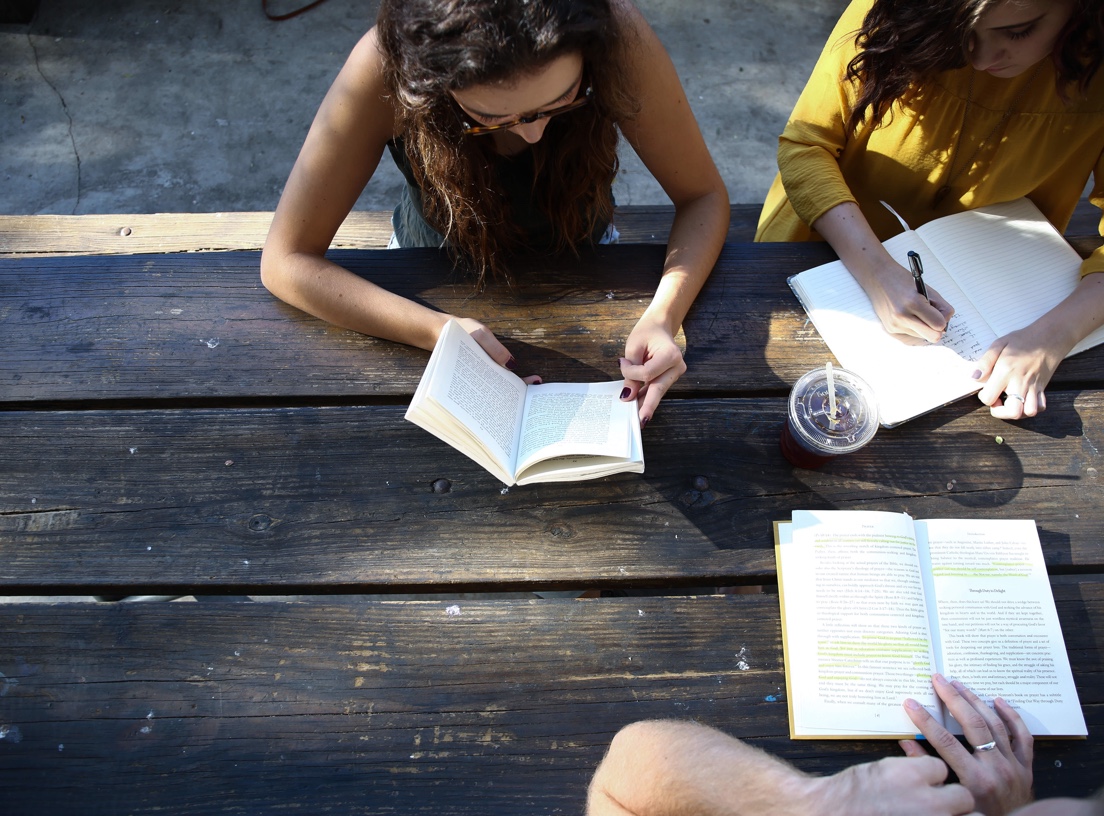 Students reading books on wooden table